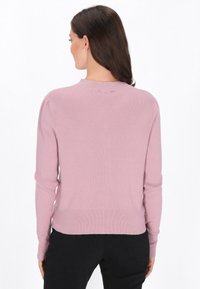 Fény rózsaszín bordás pulóver hosszú ujjakkal és magas nyakkal, testhezálló szabással és texturált anyaggal.