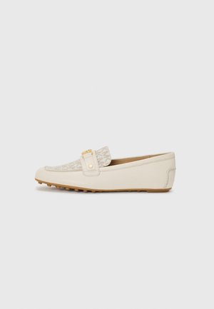 Mocassin beige avec un dessus en tissu texturé, une sangle décorative avec une quincaillerie dorée, et une semelle en caoutchouc avec de petites nervures de traction.