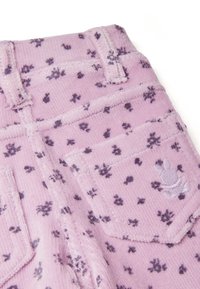Roze corduroy stof met een klein paars bloemenpatroon. Bevat zakken, stikdetails en een decoratieve borduring op de achterkant.