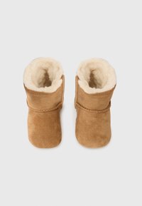 Bruna mockaläderstövlar med mjukt krämfärgat fuskpälsfoder, med en sydd kantdetalj och en lågskuren design för enkel påtagning.