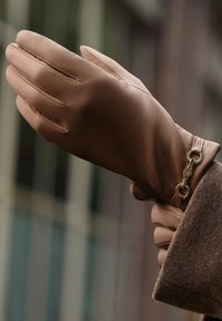 Brown leather glove featuring a three-part design and a gold chain accent at the wrist, with stitched details for added texture.