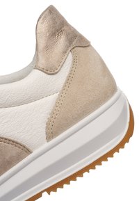 Close-up of beige and white sneaker heel with textured leather and suede panels, white midsole, and brown rubber outsole tread.