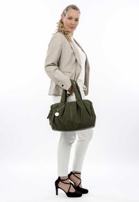 Olijfgroene stoffen tote bag met twee stevige handgrepen, voorzien van een voorkant met rits, een geplooid design en een decoratief zilveren label.