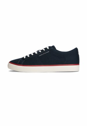 Scarpa da ginnastica bassa blu navy con lacci bianchi, striscia rossa sulla suola bianca e logo "Tommy Hilfiger" sul lato.