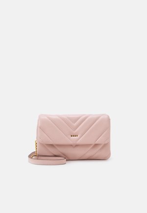 Pochette en cuir matelassé rose clair avec fermeture à rabat, logo doré et anse de poignet amovible avec détail chaîne sur un fond uni.
