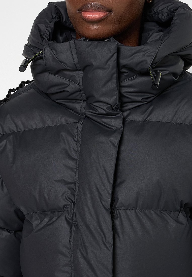 Schwarze Daunenjacke mit hohem Kragen, Reißverschluss und strukturierten Nähten. Der Stoff wirkt glänzend und glatt.
