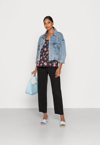Jaqueta de ganga, blusa floral, calças pretas, bolsa azul clara e sandálias com salto bloco. Conjunto casual geral com texturas e cores variadas.
