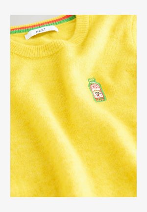 Geel sweater met een groene en rode gestreepte kraag en een geborduurd patch van een hete sausfles op de borst, gelabeld met "HOT STUFF."