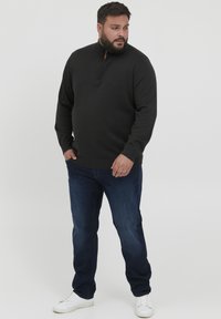 Tumedast hallist kangast poolkaelusega sviiter, millel pehme materjal, koos siniste teksade ja valgete spordijalanõudega. Lihtne disain ribatud ääre ja varrukatega.