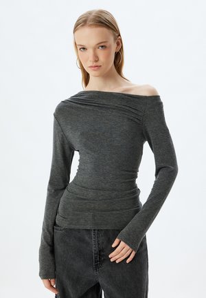 Donkergrijze off-shoulder top met lange mouwen, met een geplooide textuur over de halslijn en een getailleerd figuur.