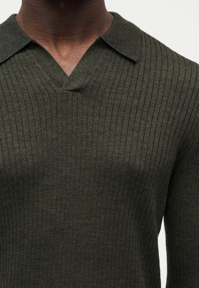 Maglione verde oliva in maglia a coste con scollo a V e collo corto strutturato, che mostra un tessuto testurizzato e un design aderente.