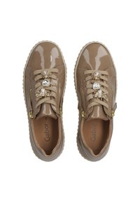 Beige Lackleder-Sneaker mit dekorativen Edelsteinen, Reißverschlüssen an den Seiten, Schnürverschluss und strukturiertem Gummisohle. Akzente in goldfarbener Hardware.