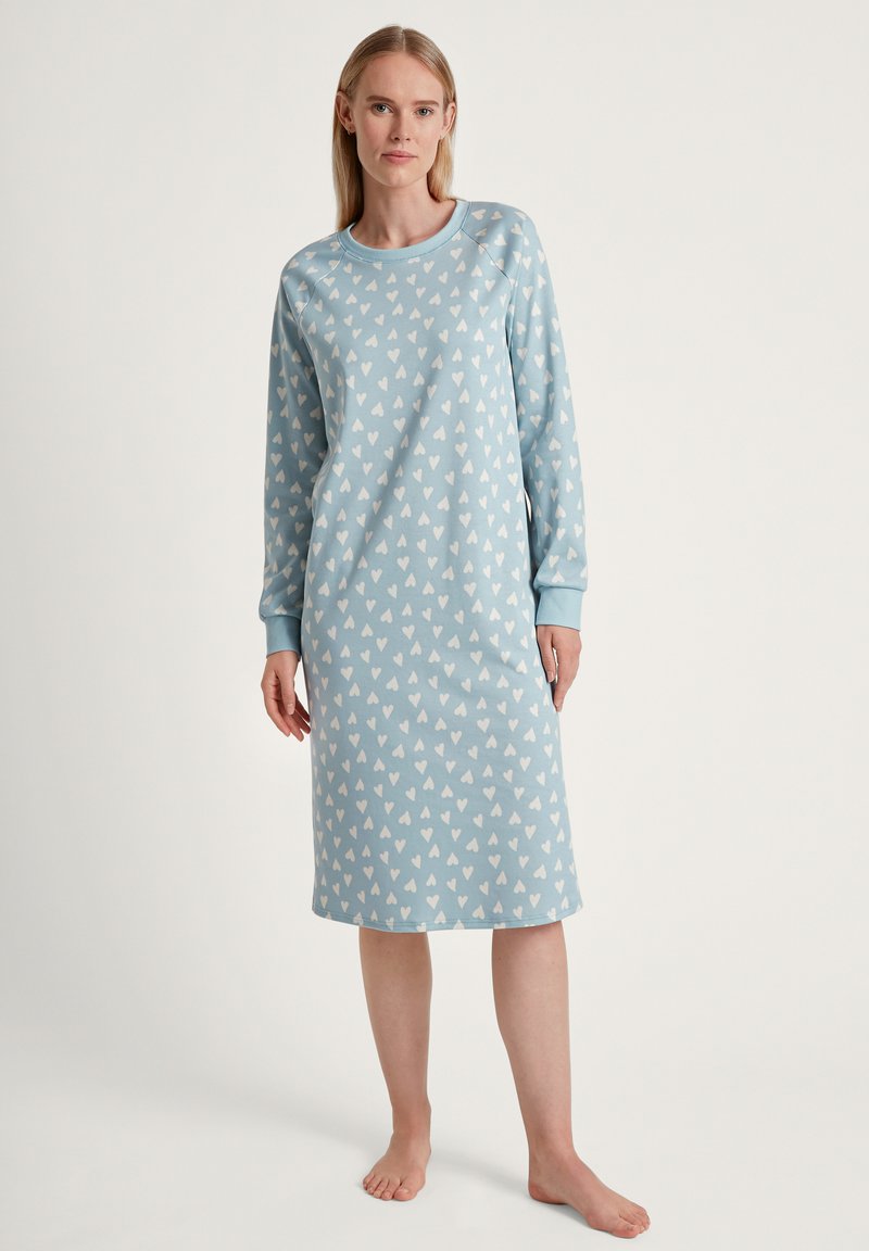 Camicia da notte a maniche lunghe in tessuto azzurro chiaro con motivo a cuori bianchi. Presenta un colletto rotondo e una texture morbida, arrivando a metà polpaccio.
