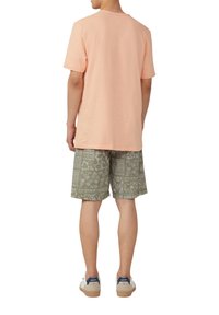 Lichtroze katoenen t-shirt gecombineerd met gestreepte olijfgroene shorts. Moderne pasvorm met een ronde hals en casual schoenen met een beige zool.