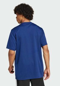 Maglietta sportiva blu navy a maniche corte, colletto tondo e vestibilità ampia. Tessuto liscio e colore uniforme, senza motivi visibili o accessori.