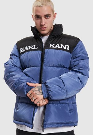 Niebieska i czarna kurtka puchowa z pikowaną powierzchnią, wysokim kołnierzem, zapięciem na zamek i nadrukowanymi logo "KARL" i "KANI" na piersi.