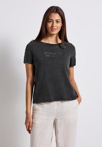 Gray cotton t-shirt with short sleeves, round neckline, and embossed text reading, “GOOD THINGS ARE COMING” on the front.
