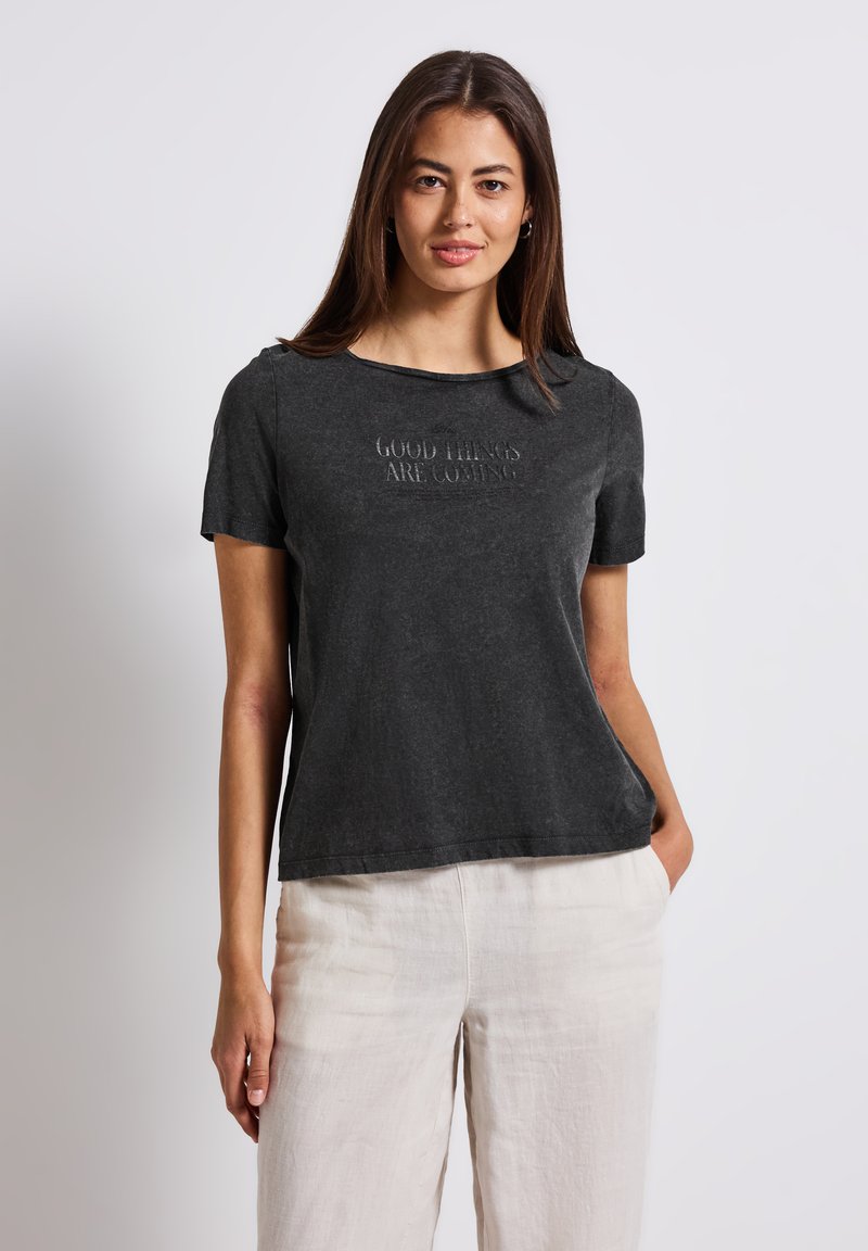 Gray cotton t-shirt with short sleeves, round neckline, and embossed text reading, “GOOD THINGS ARE COMING” on the front.