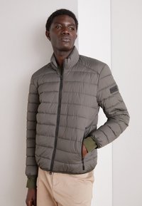 Gray puffer jacket with horizontal stitching, high collar, and zippered front. Features contrasting green cuffs and two side pockets.