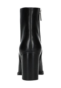 Bottes de cheville en cuir noir avec un talon épais, dotées d'une fermeture éclair à l'arrière et d'une texture lisse. Design simple sans motifs ni accents supplémentaires.