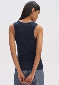 Top in cotone a costine blu navy con scollatura rotonda e design senza maniche, corpo aderente e texture liscia. La vista posteriore non presenta decorazioni.