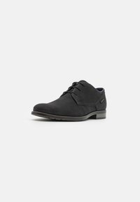 Zapato negro con cordones, fabricado en material de malla texturizada, con puntera redondeada y un tacón bajo que presenta un sutil diseño estampado en la parte superior.
