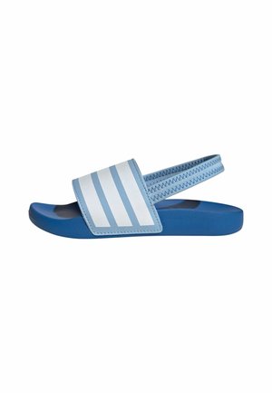 Sandalias azules de tipo slip-on con una tira ancha que presenta rayas horizontales blancas. La suela tiene textura para mayor agarre y tiene una forma redondeada.