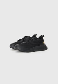 Black athletic shoes with a textured fabric upper, padded collar, and a chunky rubber sole. Features lace closure and a gold accent at the heel.