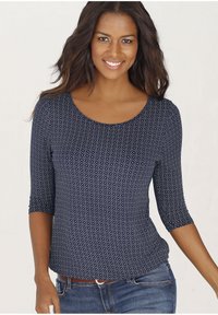 Navyblaue Bluse mit drei Viertelärmeln und einem geometrischen weißen Muster. Hergestellt aus weichem Stoff, mit Rundhalsausschnitt und taillierter Form.
