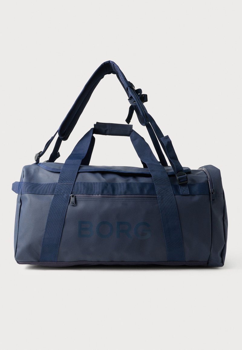 Saco de desporto azul-marinho feito de um tecido durável, com alças duplas, correia de ombro ajustável e um bolso com zíper de um lado.