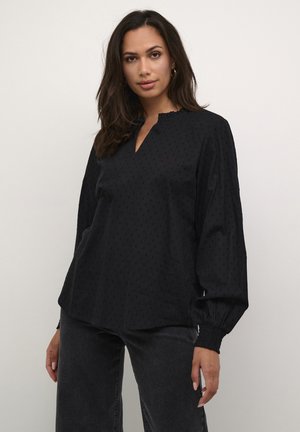 Black blouse with a textured dot pattern, featuring a V-neckline and gathered sleeves. Made from lightweight fabric.