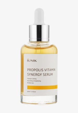 Flacon de sérum en verre transparent avec bouchon compte-gouttes argenté étiqueté Propolis Vitamin Synergy Serum, nourrissant et éclaircissant, 50 ml.