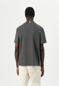 Grå kortermet polo skjorte med rett snitt, med en subtil stripet detalj på baksiden av kragen, laget av mykt stoff.