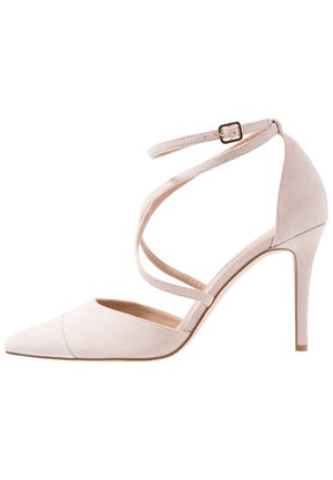 Beige højhælet sko med spids snude, slank stiletthæl, omsluttende ankremme og lille guldlås på ankremmen.