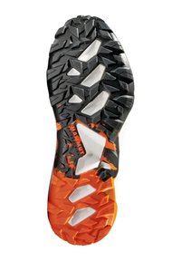 Podeszwa butów trailowych z czarnej i pomarańczowej gumy, z agresywnym wzorem bieżnika, wytłoczonymi sekcjami oraz logo "Mammut" dla lepszej przyczepności.