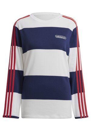 Kvinde iført blå og hvide stribede Adidas langærmet top og matchende shorts med røde striber på ærmer og sider.