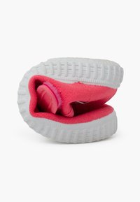 Scarpa rosa con un esterno in tela testurizzata e una suola in gomma bianca, mostrata da un lato, parzialmente arrotolata per rivelare l'interno.