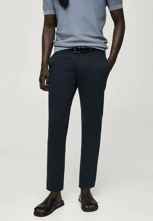 Pantaloni navy slim-fit dintr-un material ușor, cu o textură netedă și buzunare laterale, asortați cu sandale negre.