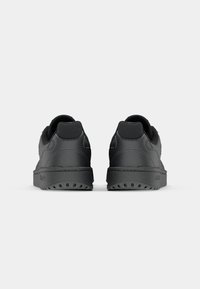 Svarta lädersneakers med en vadderad krage, texturerad yta och en gummisula med ett mönster. Minimalistisk design utan synliga logotyper.