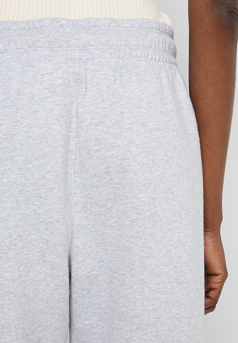 Szare dresy z elastycznym paskiem w talii, z delikatną teksturą melanżową i bocznymi szwami. Materiał wydaje się miękki i wygodny.