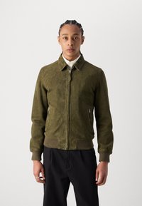 Giacca bomber in suede verde oliva con chiusura a zip, tasche laterali e polsini a costine. Presenta un colletto classico e una texture liscia.