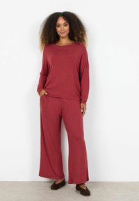 Súprava pohodlného oblečenia bordovej farby z mäkkej látky; zahŕňa nohavice s širokými nohavicami a voľný dlhý rukáv s okrúhlym výstrihom.