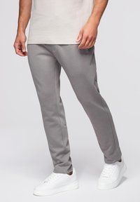 Grijze joggingbroek van zachte stof, taps toelopend ontwerp, met zijzakken, gecombineerd met witte sneakers. Minimalistische en functionele uitstraling.