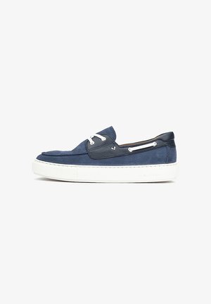 Mocassin bateau en daim bleu marine et cuir avec lacets blancs et semelle en caoutchouc blanche épaisse, présenté en profil latéral sur fond blanc.