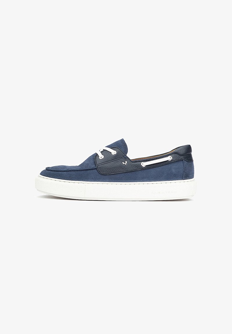 Mocassin bateau en daim bleu marine et cuir avec lacets blancs et semelle en caoutchouc blanche épaisse, présenté en profil latéral sur fond blanc.