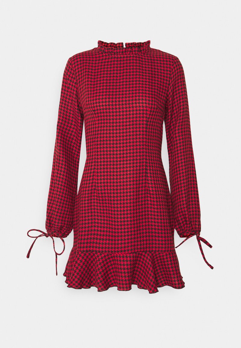 Robe à manches longues à motif pied-de-poule rouge et noire avec un ourlet à volants, un col montant et des poignets noués sur fond blanc.