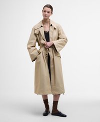 Beige, waterproof trench coat with a large collar, wide sleeves, and a tie belt. Model wears a black dress and brown textured socks.