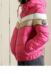 Polstret jakke i livlig pink med vandrette hvide og beige striber. Har hætte, lynlås foran og ribbede manchetter. Casual design.