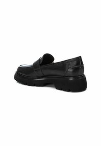 Zapatos de piel negra tipo mocasín con puntera redondeada, suela de goma gruesa y detalle de tira en la parte delantera. Acabado liso con sutiles acentos de costura.