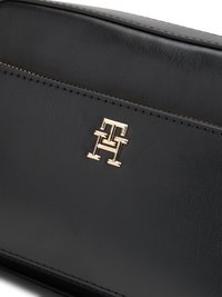 Black leather bag with a smooth texture, featuring a gold-tone logo and stitching. Design includes a zipper and sleek, minimal profile.